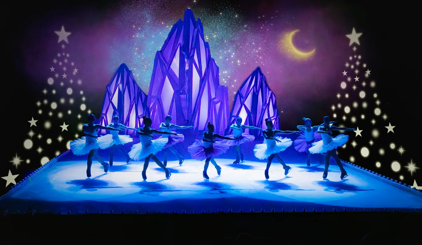 A line of skaters in white in front of a purple ice-crystal set with Christmas trees drawn in lights